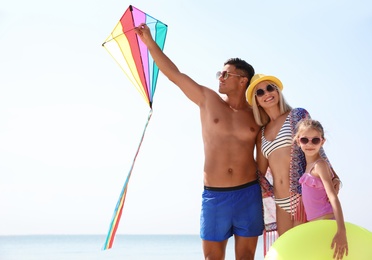 Photo of Happy family with inflatable ring and kite at beach on sunny day