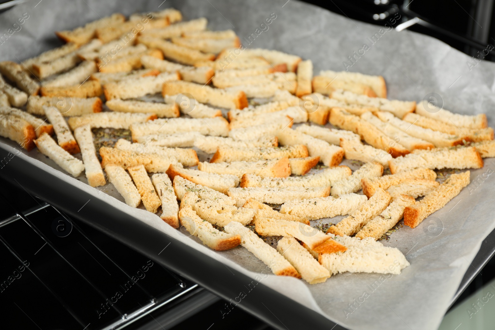 Photo of Taking baking pan with hard chucks out of oven, closeup