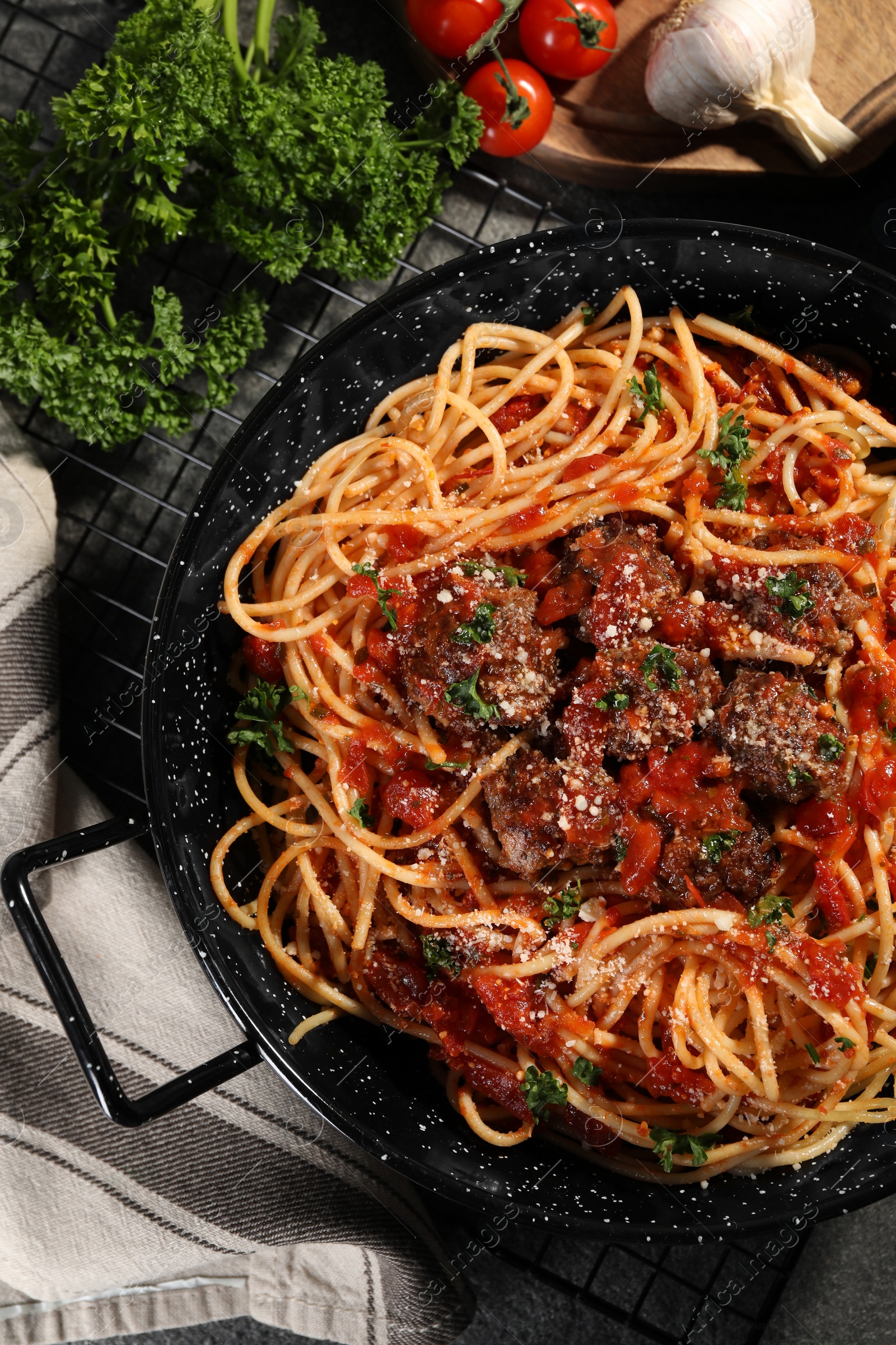 Photo of Delicious pasta with meatballs and tomato sauce near ingredients on grey table, flat lay