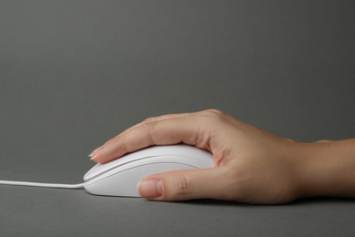 Photo of Woman using wired computer mouse on grey background, closeup