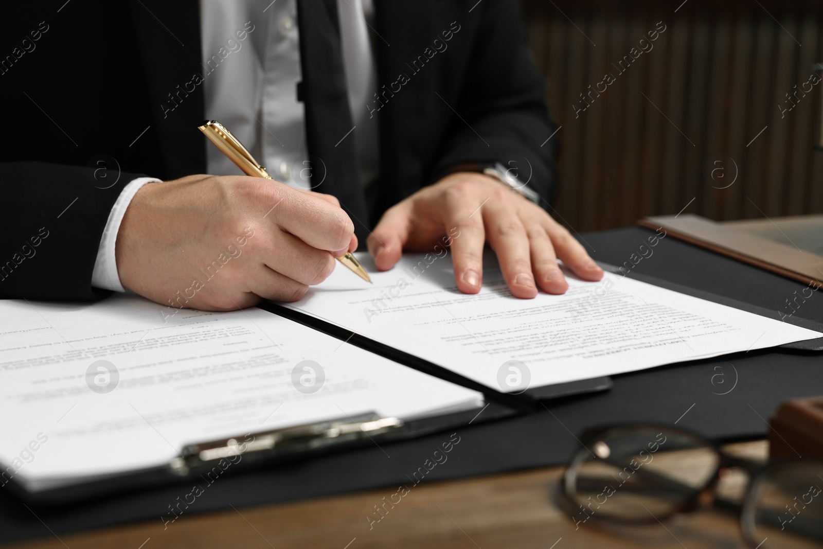 Photo of Lawyer working with documents at wooden table in office, closeup