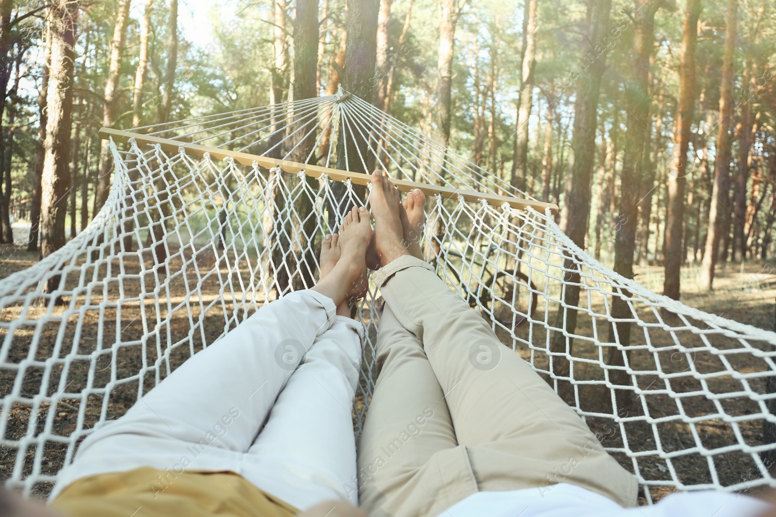 Photo of Couple resting in hammock outdoors on summer day, closeup of legs