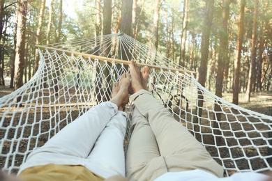 Photo of Couple resting in hammock outdoors on summer day, closeup of legs