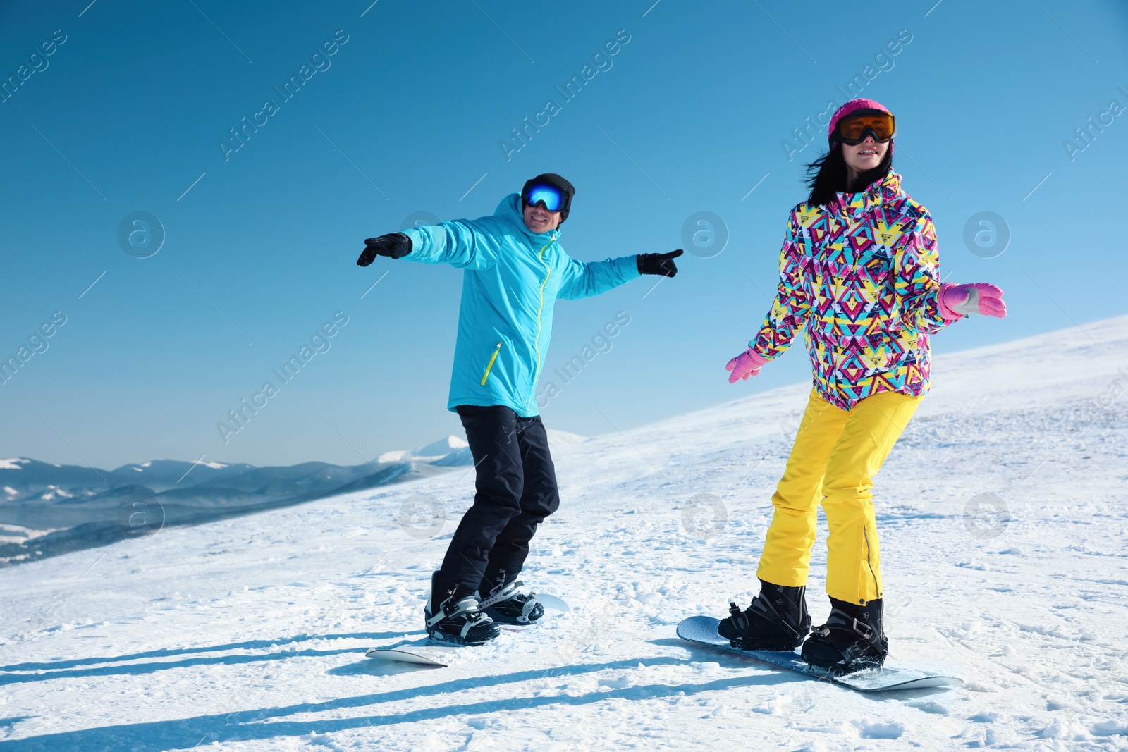 Photo of Couple snowboarding on snowy hill. Winter vacation