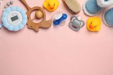 Flat lay composition with pacifiers and other baby stuff on pink background