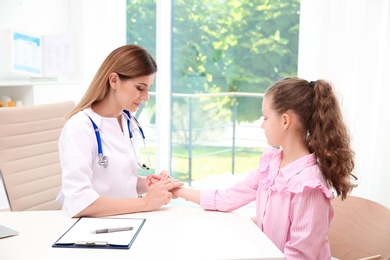 Doctor checking little girl's pulse in hospital