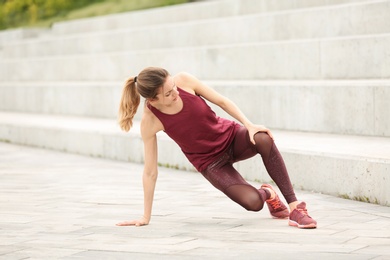 Woman in sportswear suffering from knee pain on stairs