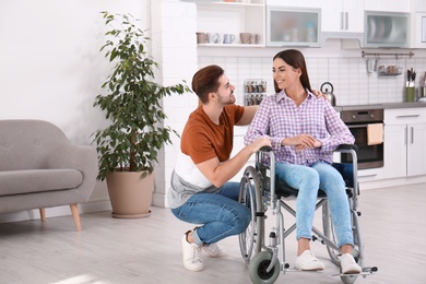 Young man with woman in wheelchair indoors