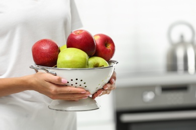 Photo of Woman holding colander of apples indoors, closeup. Space for text