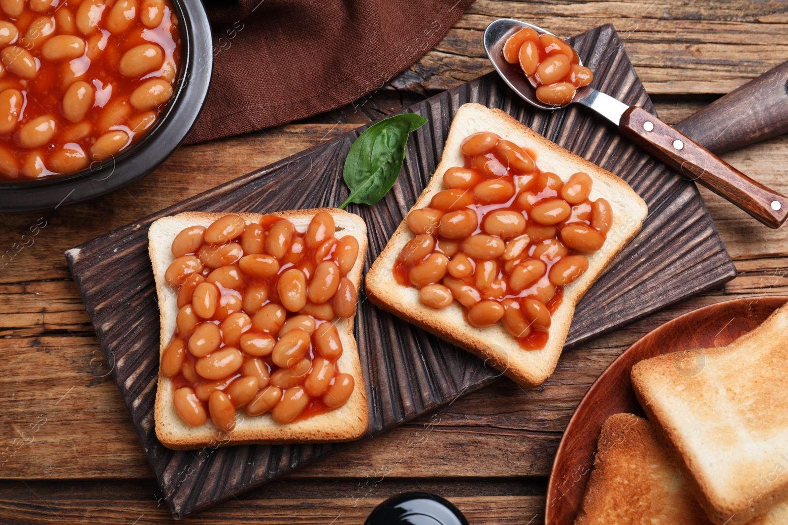 Photo of Toasts with delicious canned beans on wooden table, flat lay