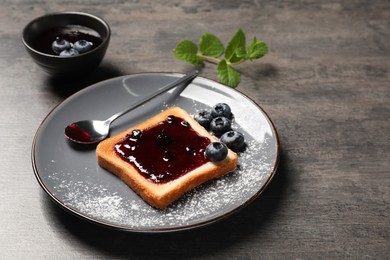 Photo of Delicious toast served with jam and blueberries on grey wooden table
