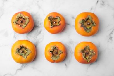 Photo of Delicious ripe juicy persimmons on white marble table, flat lay