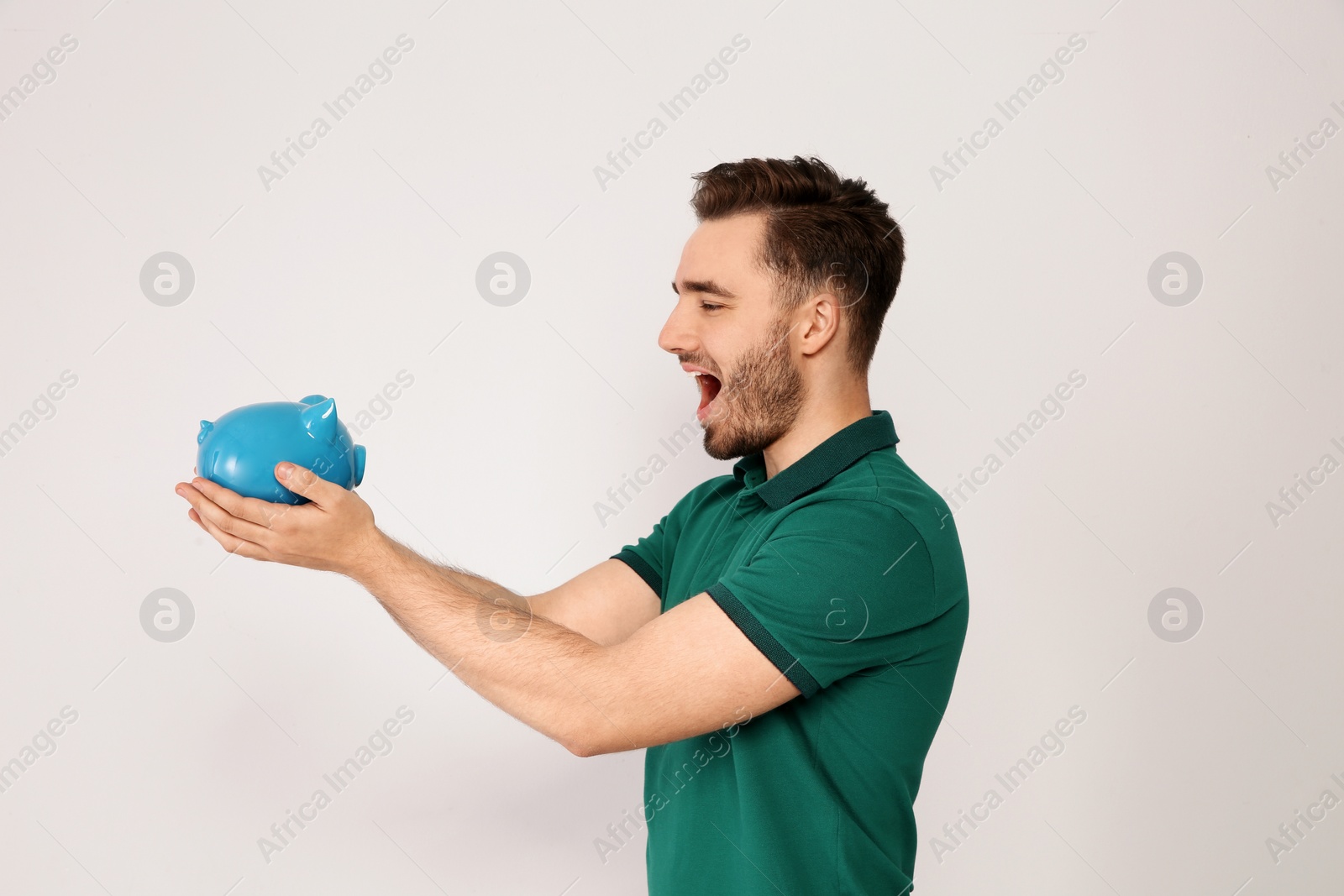 Photo of Young man with piggy bank on light background