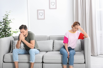 Photo of Couple ignoring each other after argument in living room. Relationship problems