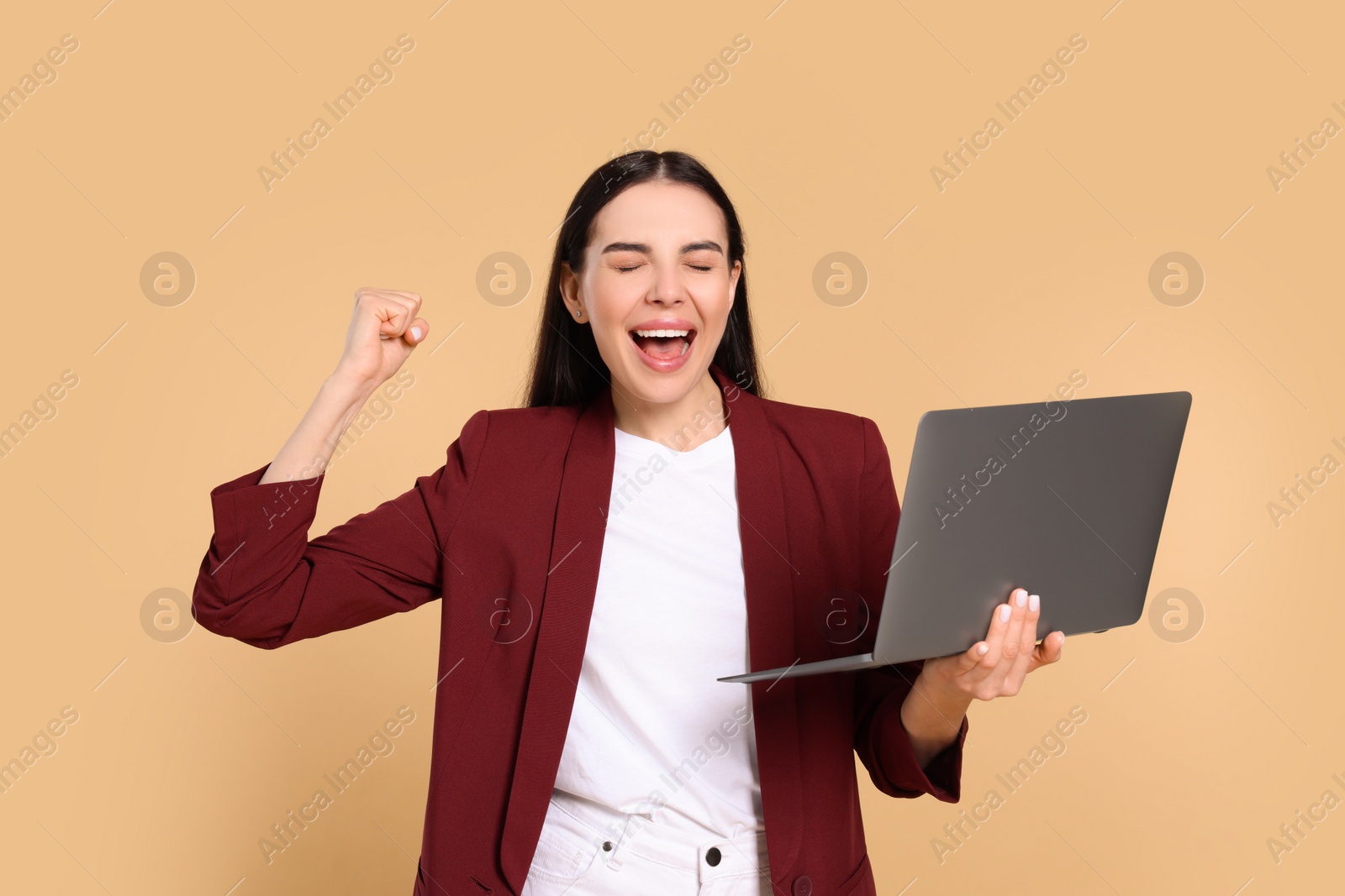 Photo of Cheerful woman with laptop on beige background