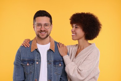 International dating. Portrait of happy couple on orange background