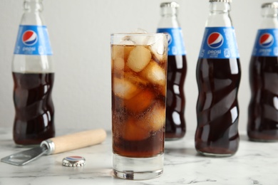 MYKOLAIV, UKRAINE - FEBRUARY 10, 2021: Glass and bottles of Pepsi on white marble table