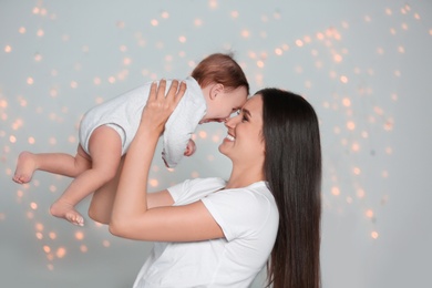 Photo of Young mother with her cute little baby against defocused lights