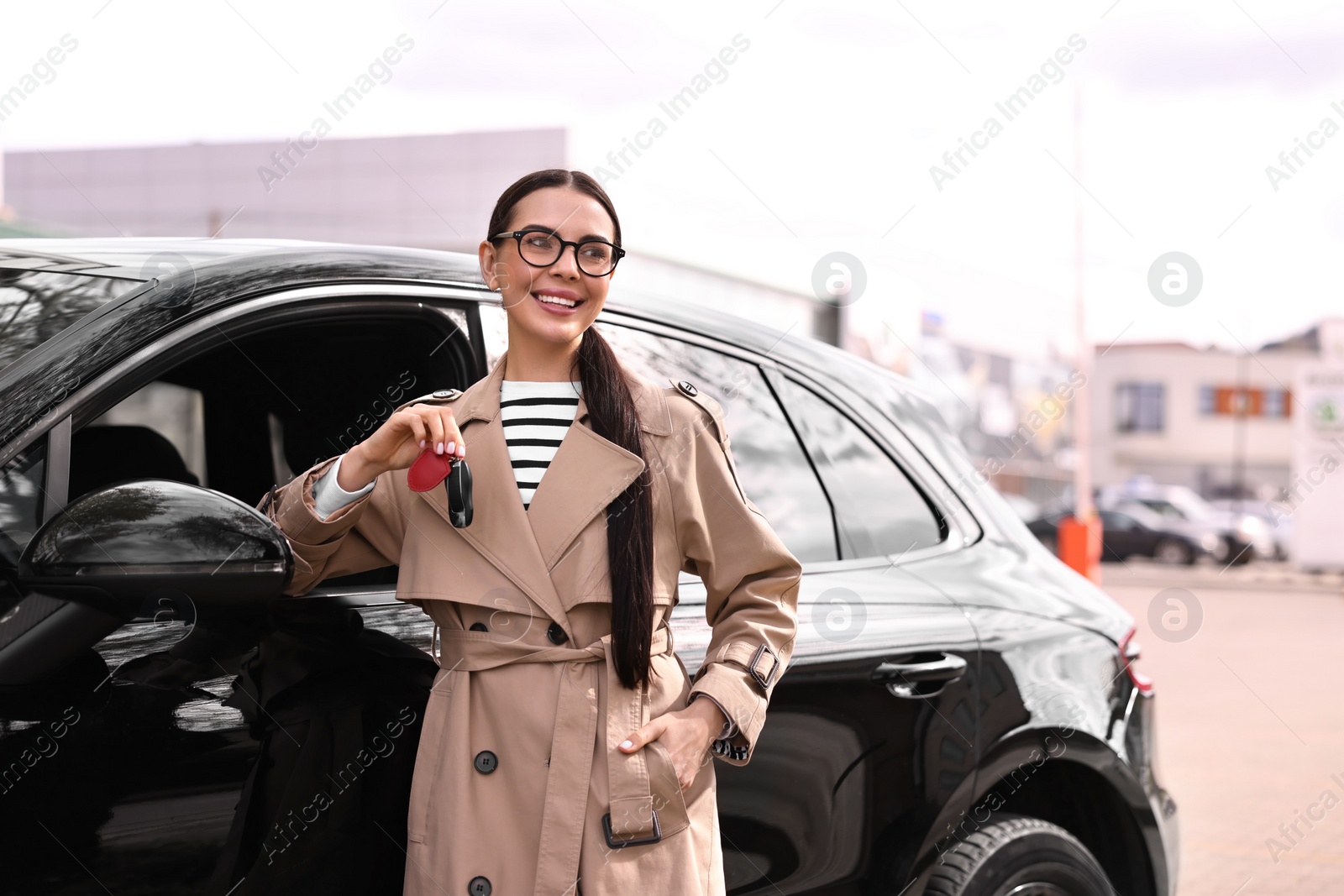 Photo of Woman holding car flip key near her vehicle outdoors