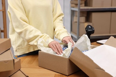 Post office worker packing parcel at wooden table indoors, closeup