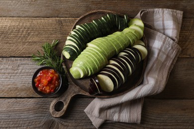 Photo of Different cut vegetables, rosemary and dressing for ratatouille on wooden table, flat lay