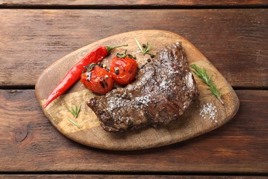 Photo of Delicious roasted beef meat, vegetables and spices on wooden table, top view