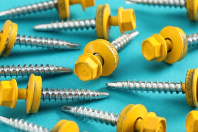 Yellow self-tapping screws on light blue background, closeup