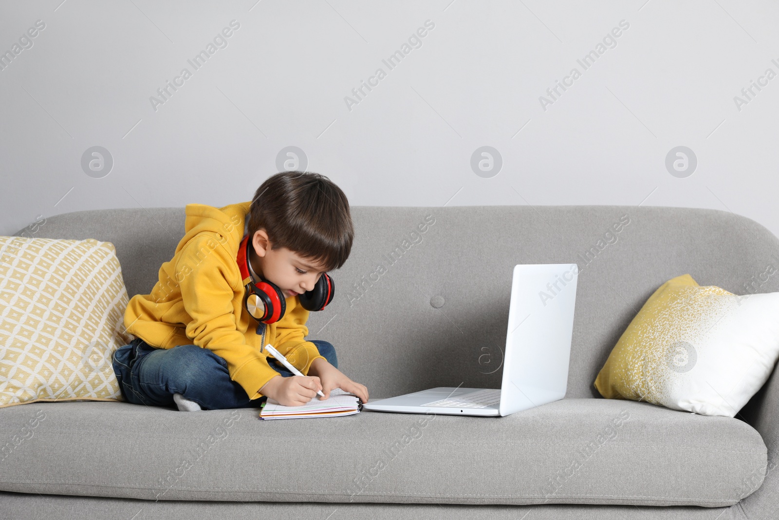 Photo of Cute little boy with modern laptop studying online at home. E-learning