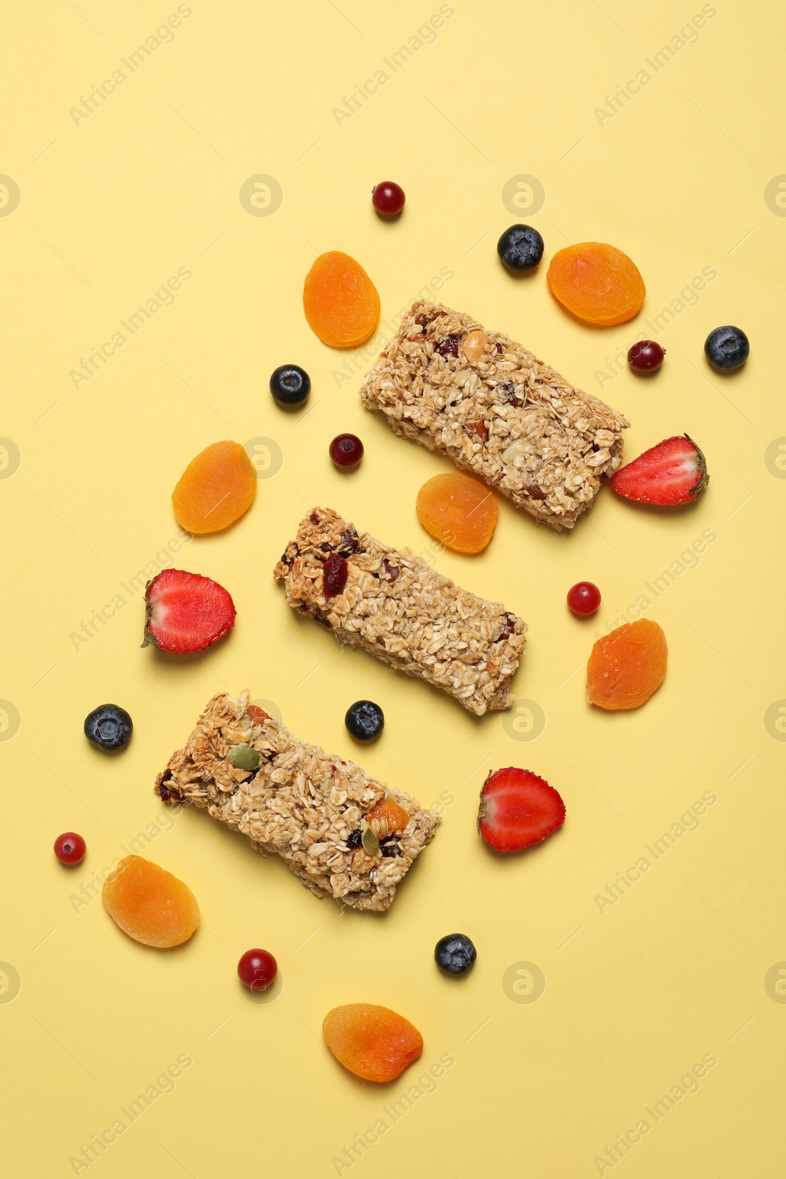 Photo of Tasty granola bars and fruits on yellow background, flat lay