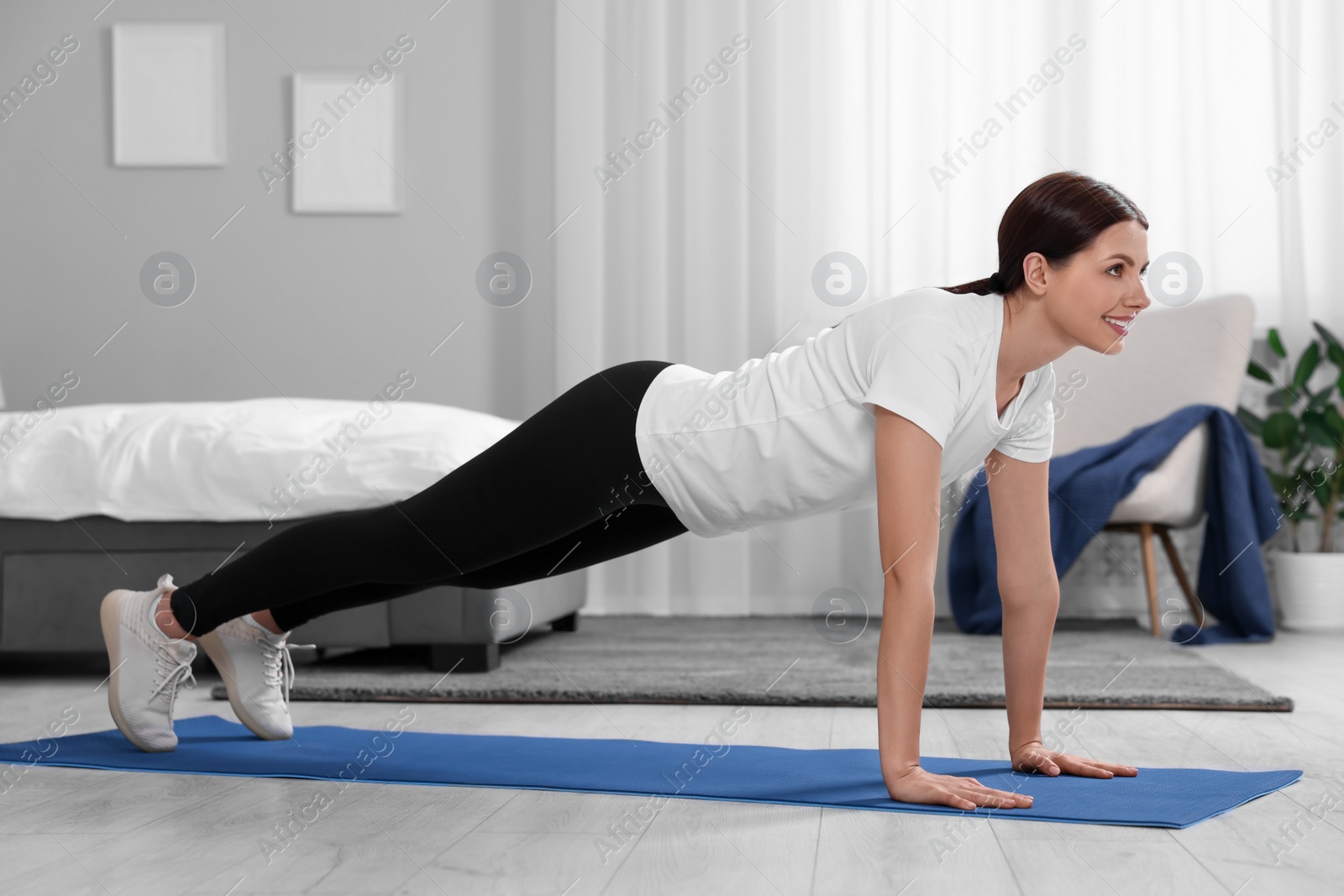 Photo of Happy woman doing plank exercise at home. Morning routine