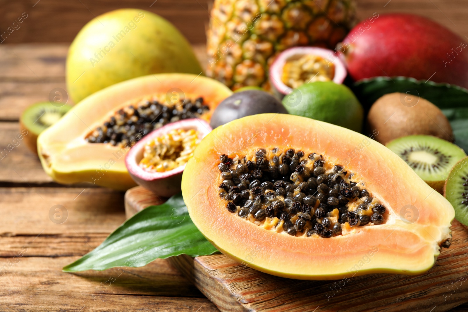 Photo of Fresh ripe papaya and other fruits on wooden table. Space for text