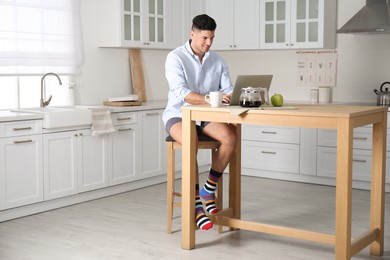 Photo of Businessman in shirt and underwear working on laptop at home