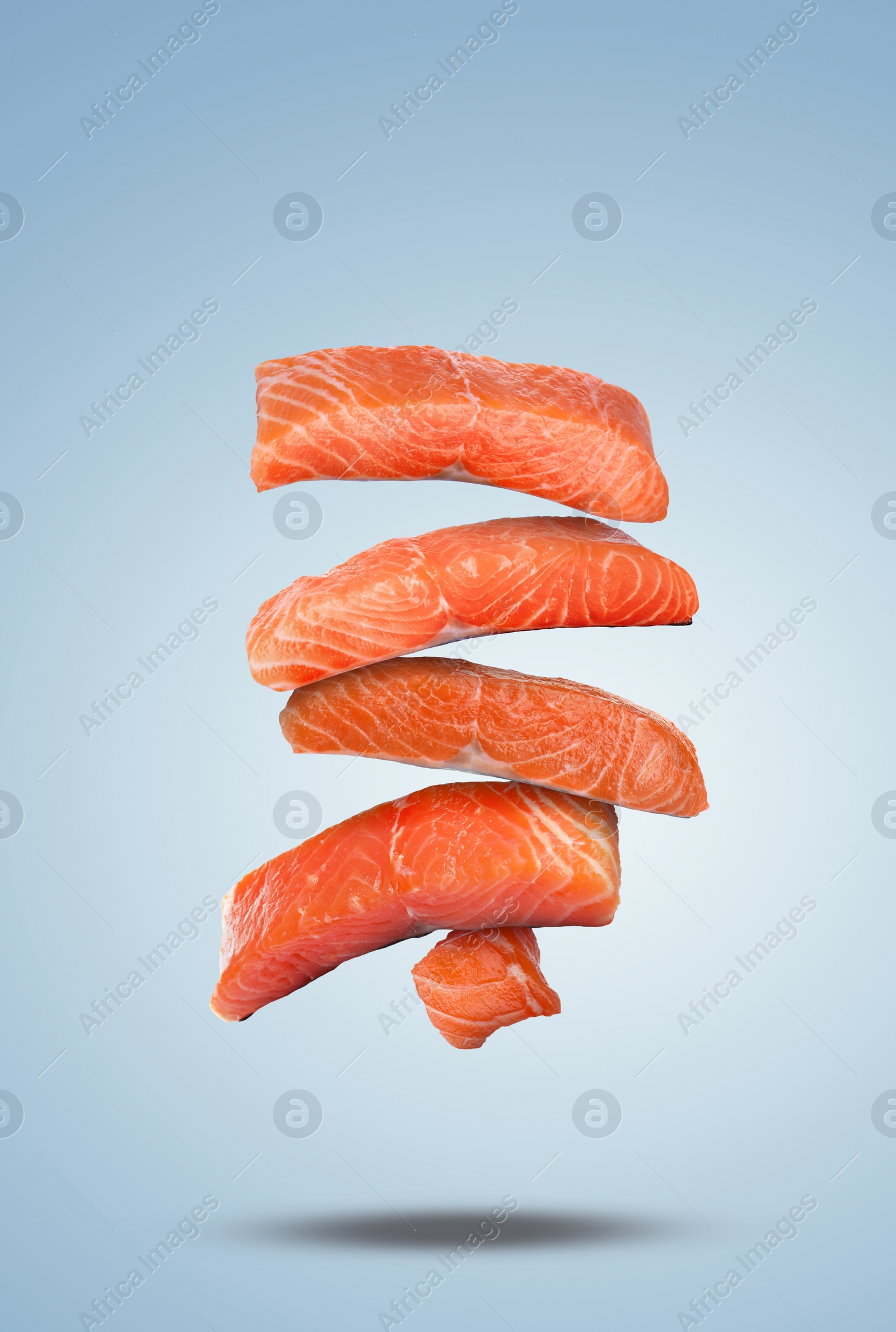 Image of Cut fresh salmon falling on pale light blue gradient background