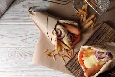 Delicious pita wrap with sausages, vegetables and potato fries on white wooden table, top view. Space for text