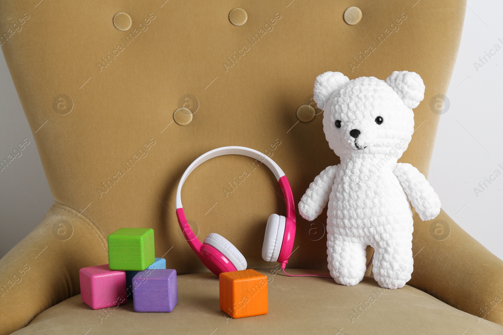 Photo of Baby songs. Toy bear, headphones and cubes on armchair