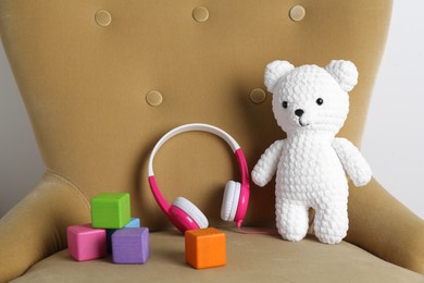 Baby songs. Toy bear, headphones and cubes on armchair