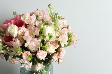 Photo of Beautiful bouquet of fresh flowers in vase on light background. Space for text