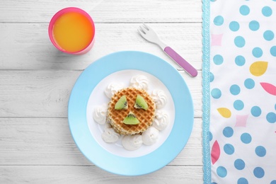 Photo of Tasty waffles served with whipped cream and juice on white wooden table, flat lay. Creative idea for kids breakfast