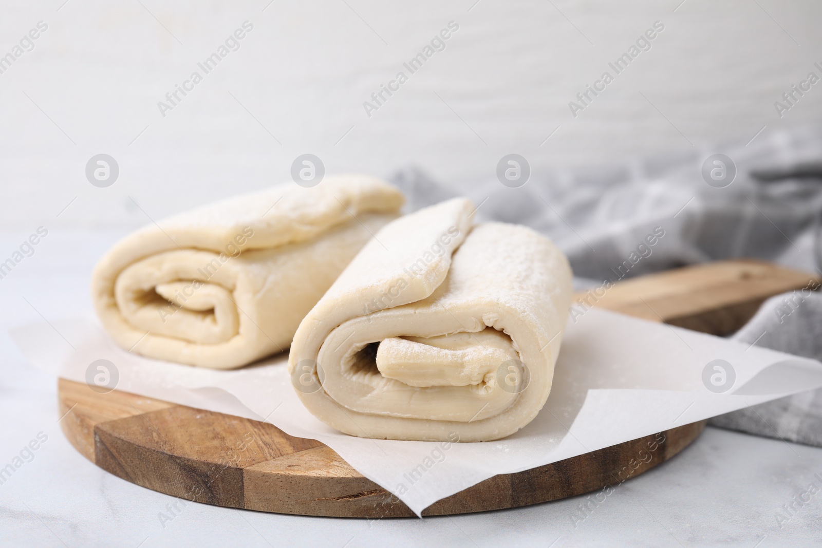 Photo of Raw puff pastry dough on white marble table, closeup