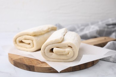 Raw puff pastry dough on white marble table, closeup