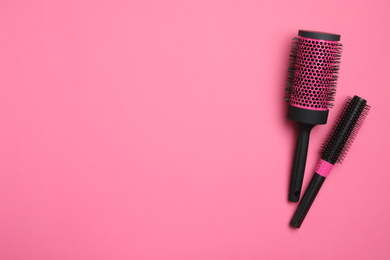 Photo of Modern round hair brushes on pink background, flat lay. Space for text