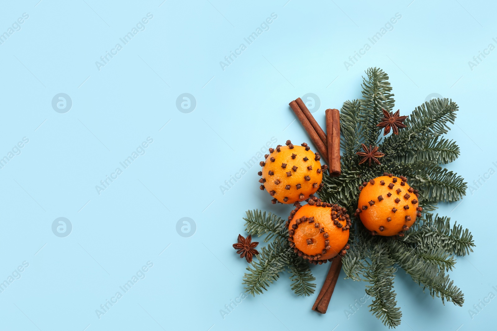 Photo of Flat lay composition with pomander balls made of fresh tangerines on light blue background. Space for text
