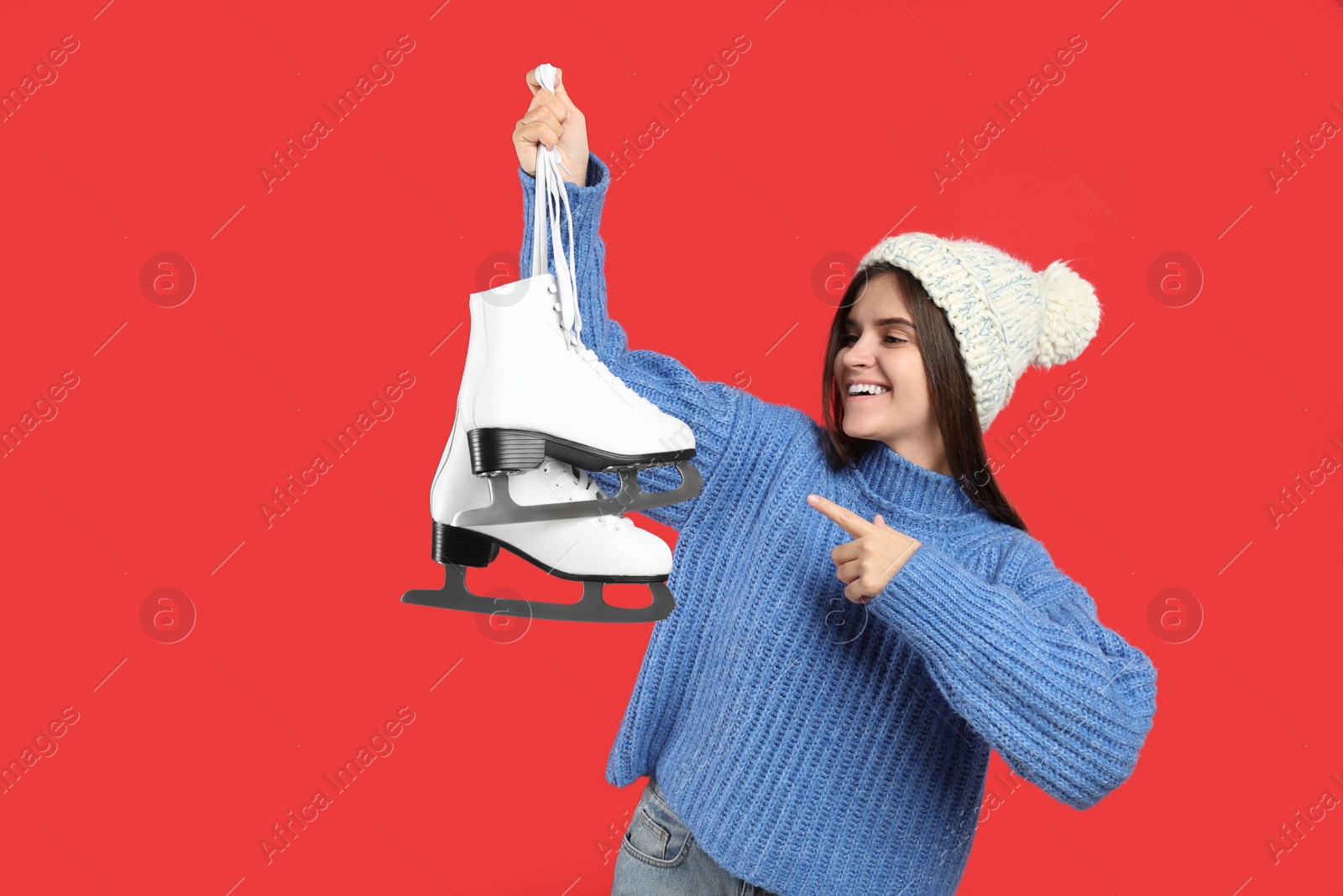 Photo of Happy woman with ice skates on red background