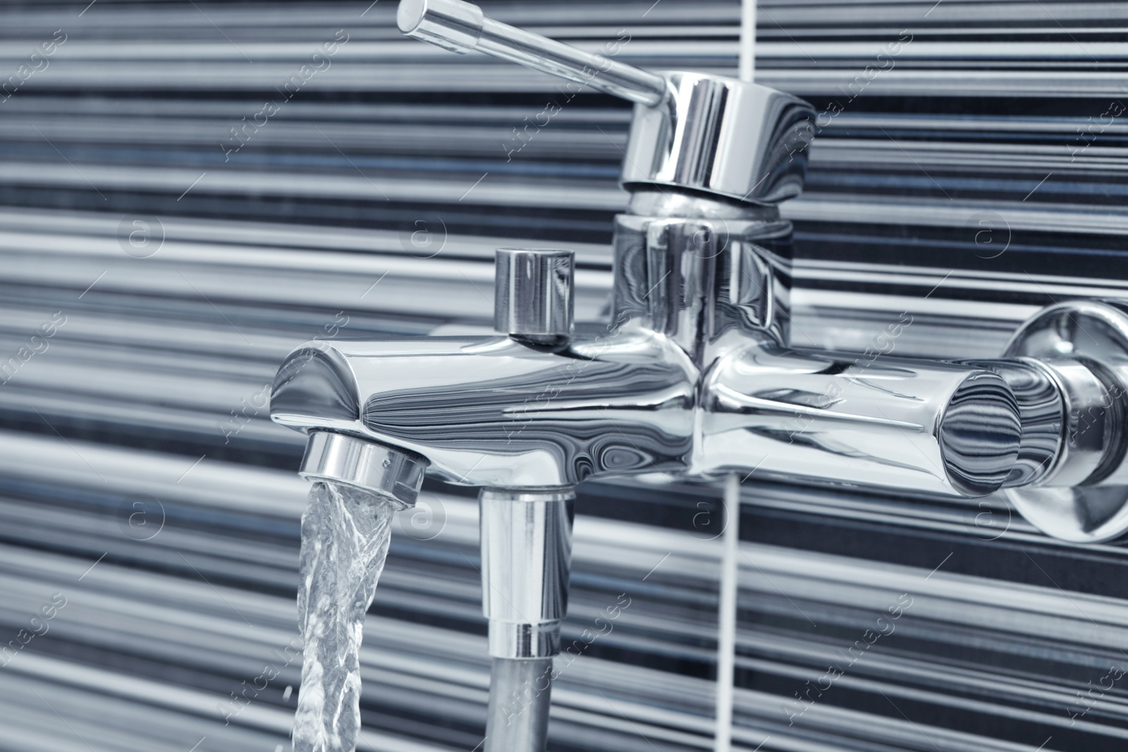 Photo of Water flowing from bath tap installed on black and white wall