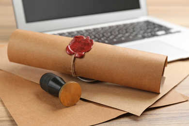 Photo of Notary's public pen and sealed document near laptop on wooden table, closeup