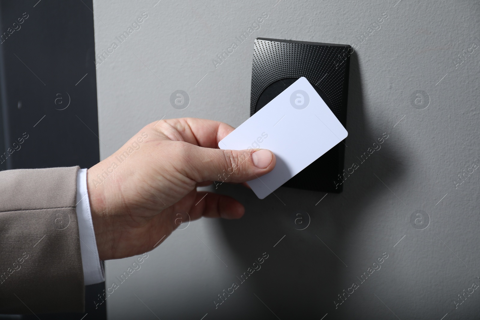 Photo of Man opening magnetic door lock with key card, closeup. Home security