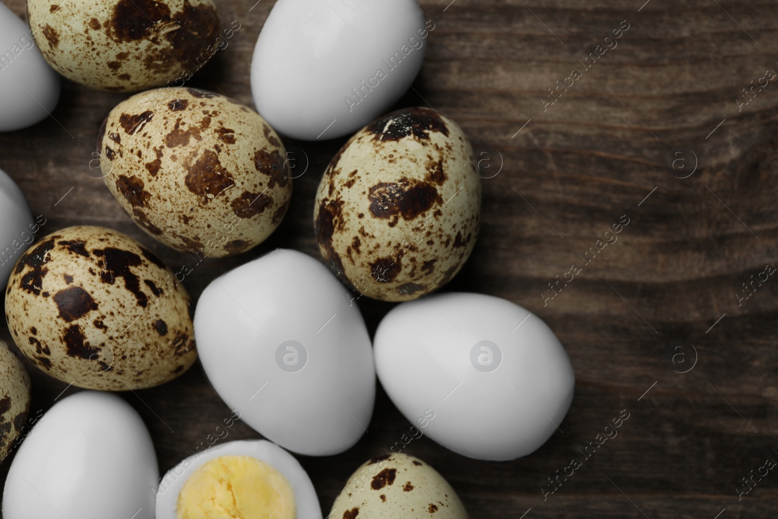 Photo of Peeled and unpeeled hard boiled quail eggs on wooden table, flat lay. Space for text
