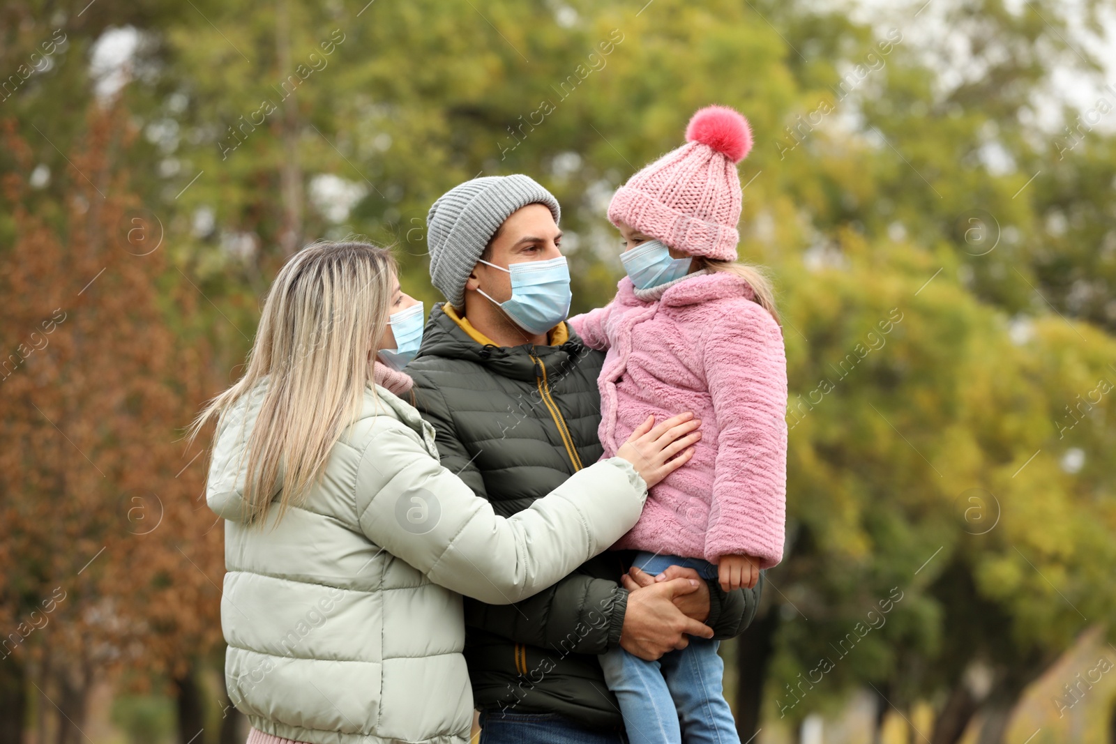 Photo of Family in medical masks outdoors on autumn day. Protective measures during coronavirus quarantine