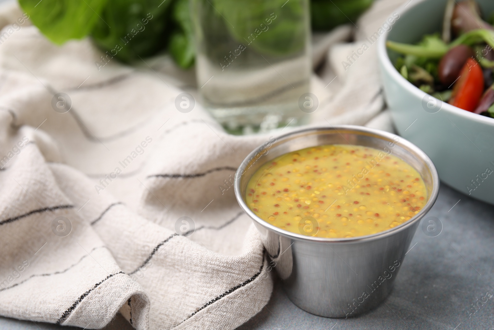 Photo of Tasty vinegar based sauce (Vinaigrette) in bowl on grey table, closeup. Space for text