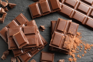 Pieces of tasty chocolate on slate plate, top view